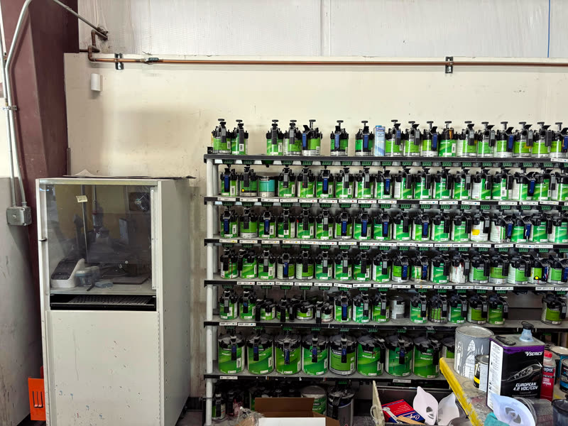 A rack of paint tinters in rows against the wall, with the mixing machine beside it.