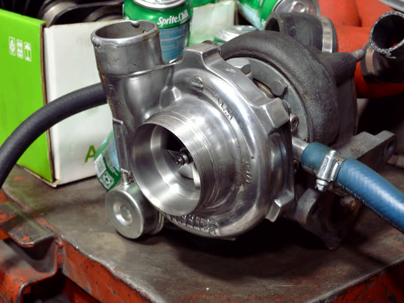A turbocharger sitting on a tool chest, its compressor housing open to the light.